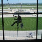 Professional window cleaner hanging outside building